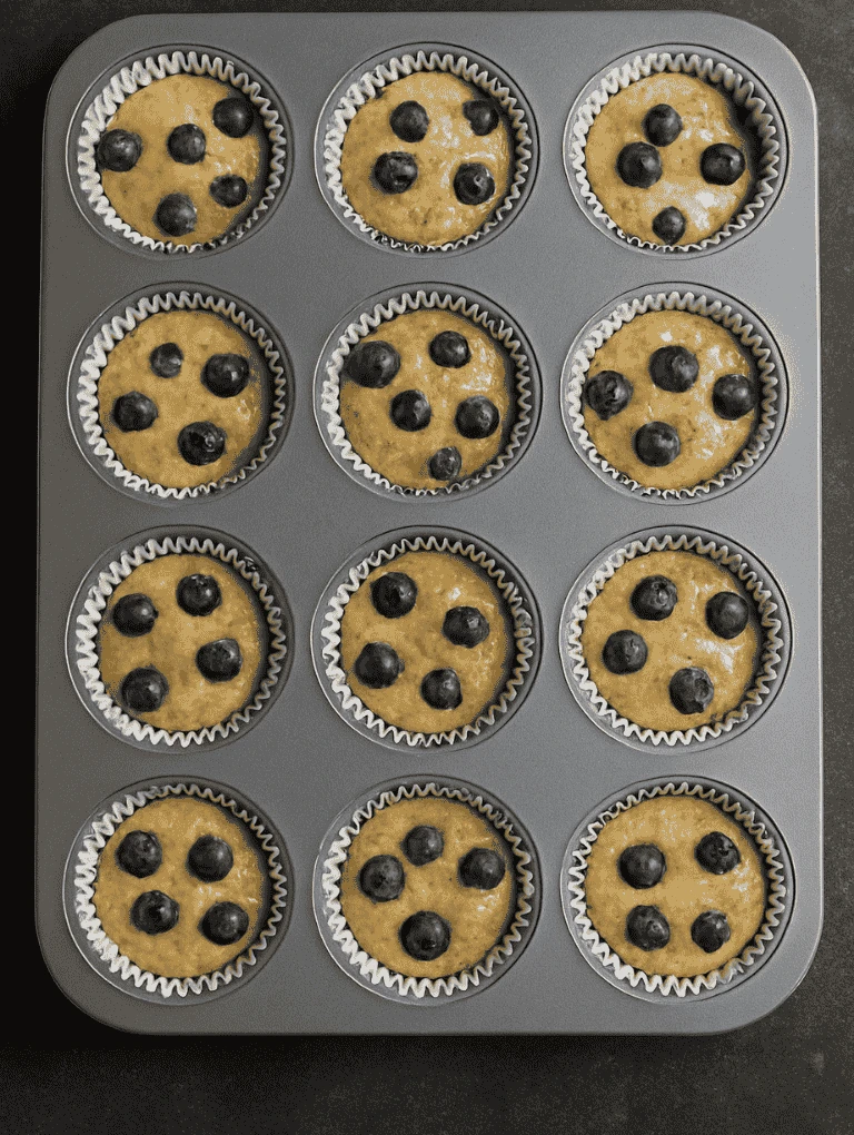 Muffins rising in the oven in a metal muffin pan