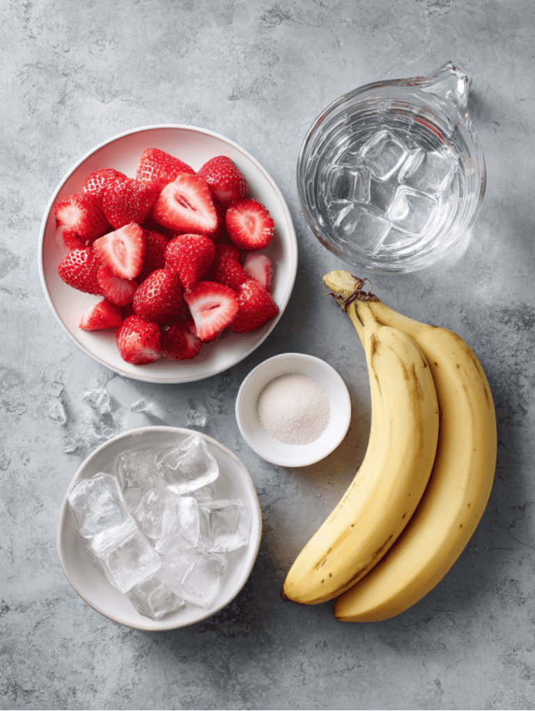 Overhead flat lay of Jetty Punch ingredients: strawberries, bananas, sugar, ice cubes, and water on a gray countertop.