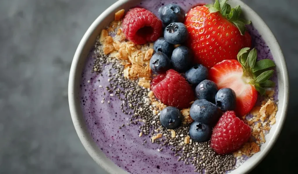 Creamy mixed berry smoothie bowl with blueberries, raspberries, granola, and chia seeds.