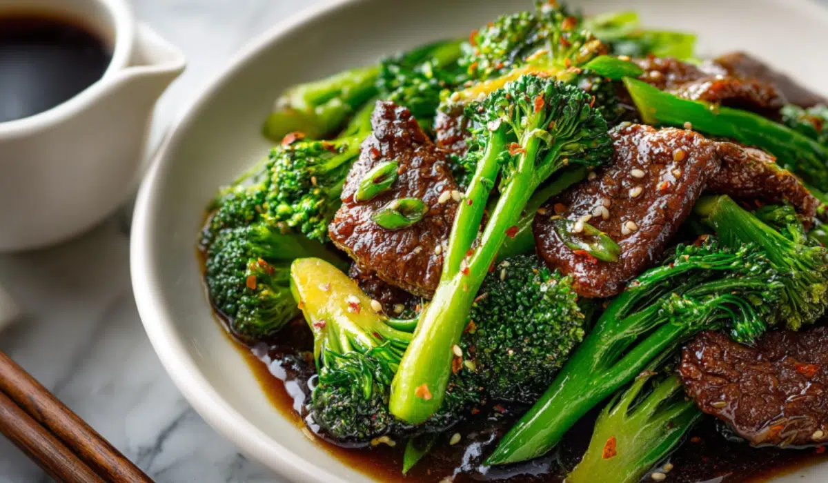 Overhead view of Chinese beef and broccoli stir-fry with glossy sauce and tender beef, served on marble surface with chopsticks.