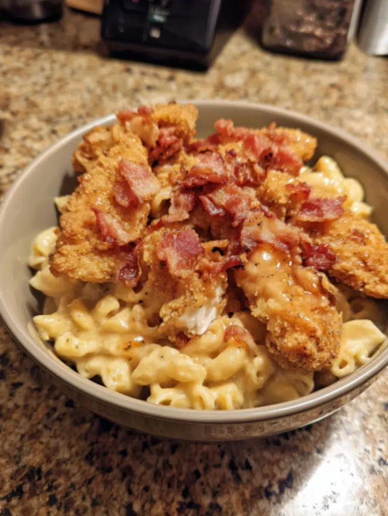 Finished Honey Pepper Chicken Mac and Cheese served in a bowl, topped with bacon and parsley, photographed on a clean kitchen counter.