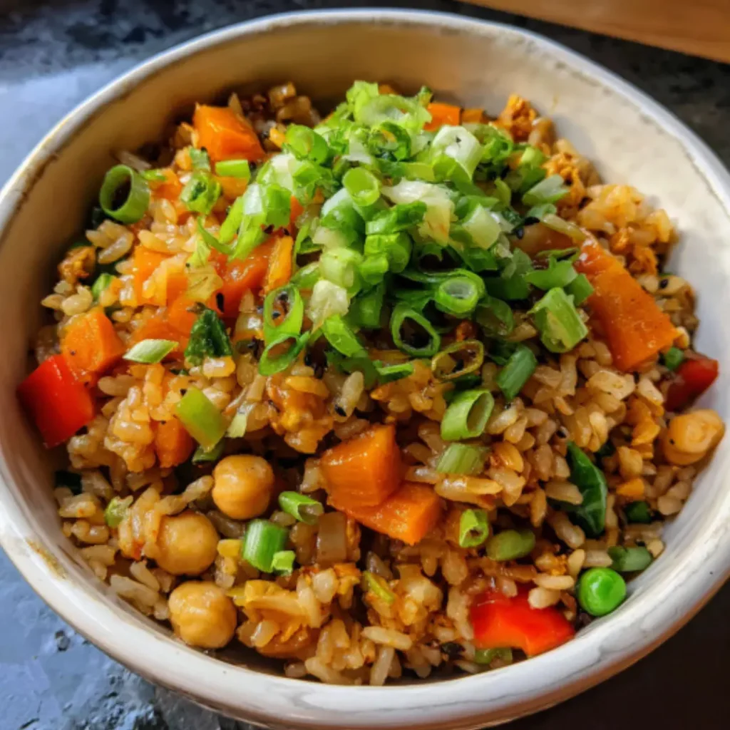 A serving of vegan fried rice in a bowl with a spoon, garnished with green onions.