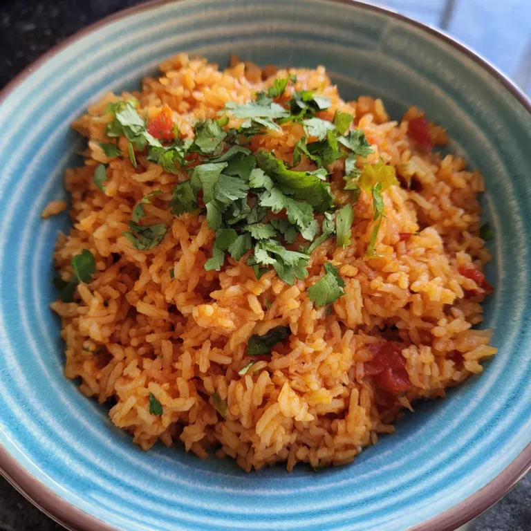 Vibrant bowl of Traditional Mexican Rice garnished with fresh cilantro in a turquoise bowl.