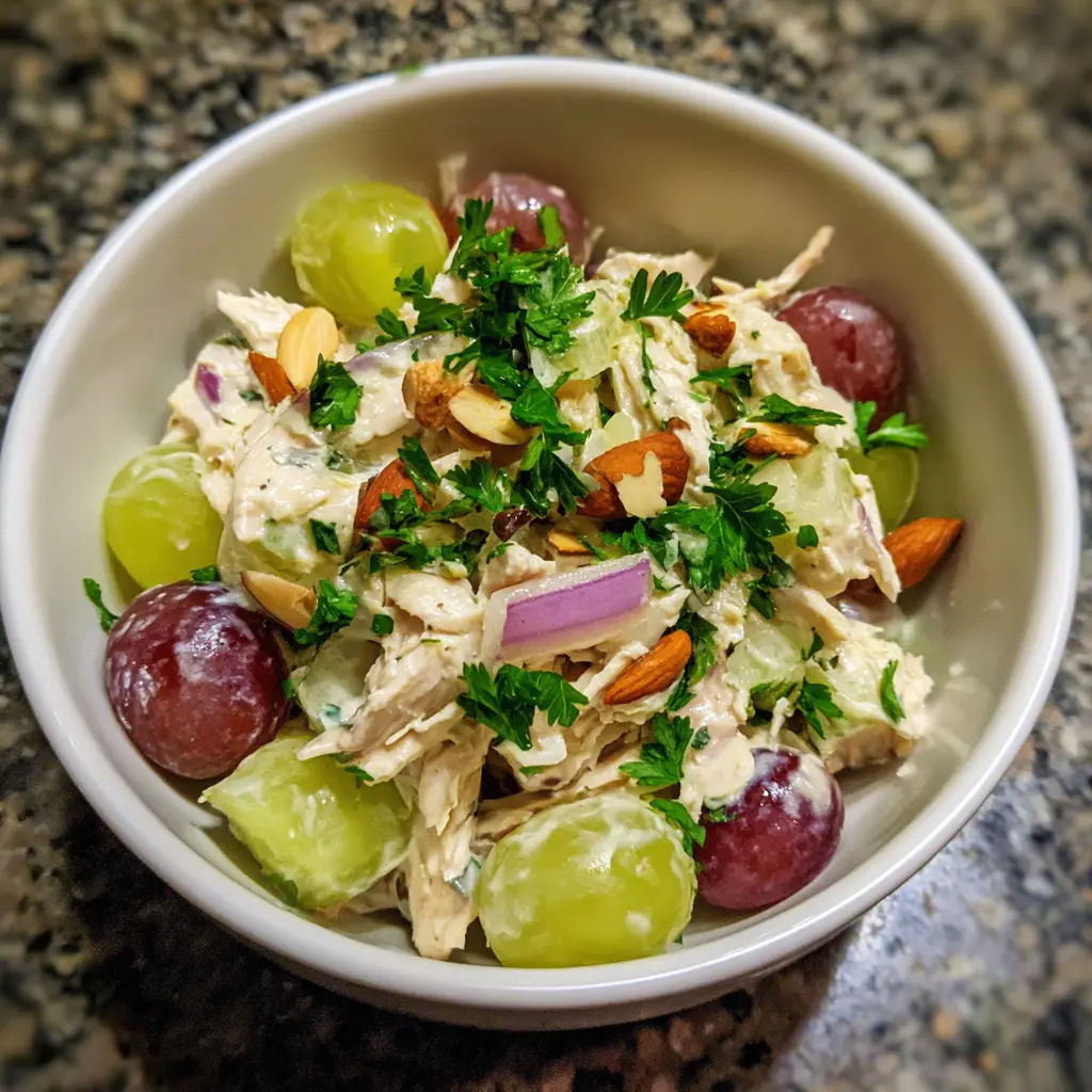 Vibrant Greek Yogurt Chicken Salad with grapes, celery, red onion, and toasted almonds in a white bowl.