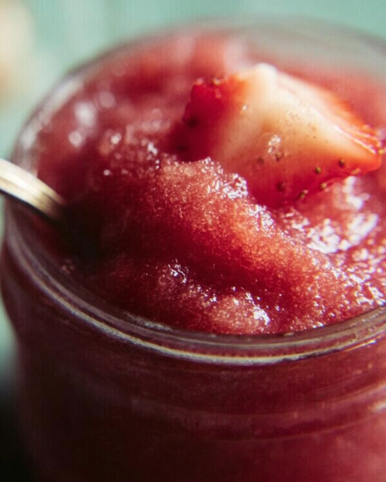 Smooth, vibrant pink rhubarb butter spread generously on a piece of toasted bread, glistening in natural light.